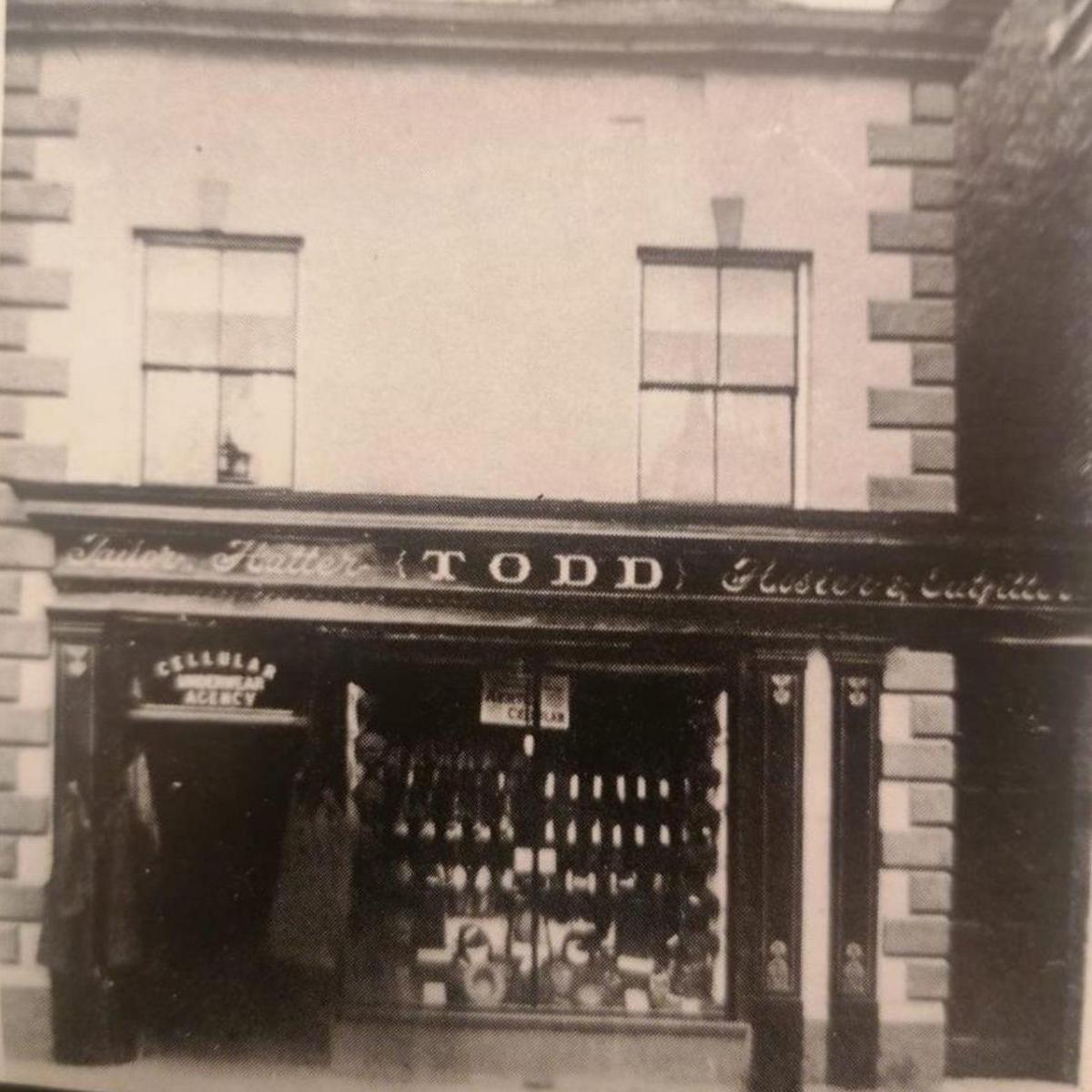 A grainy, black and white photograph of a haberdashery shop front showing the word Todd above the window. 