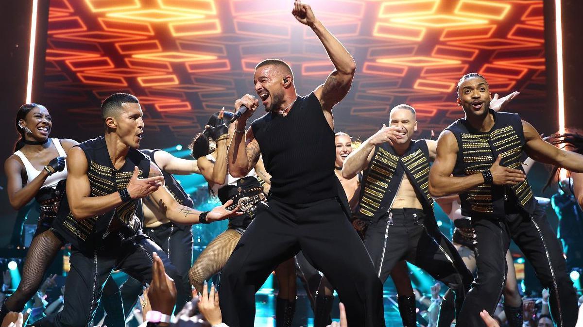Ricky Martin, seen wearing a black vest, performs alongside backing dancers