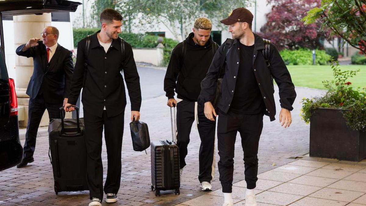 Ben Davies, Chris Mepham and Wes Burns carry luggage from a car