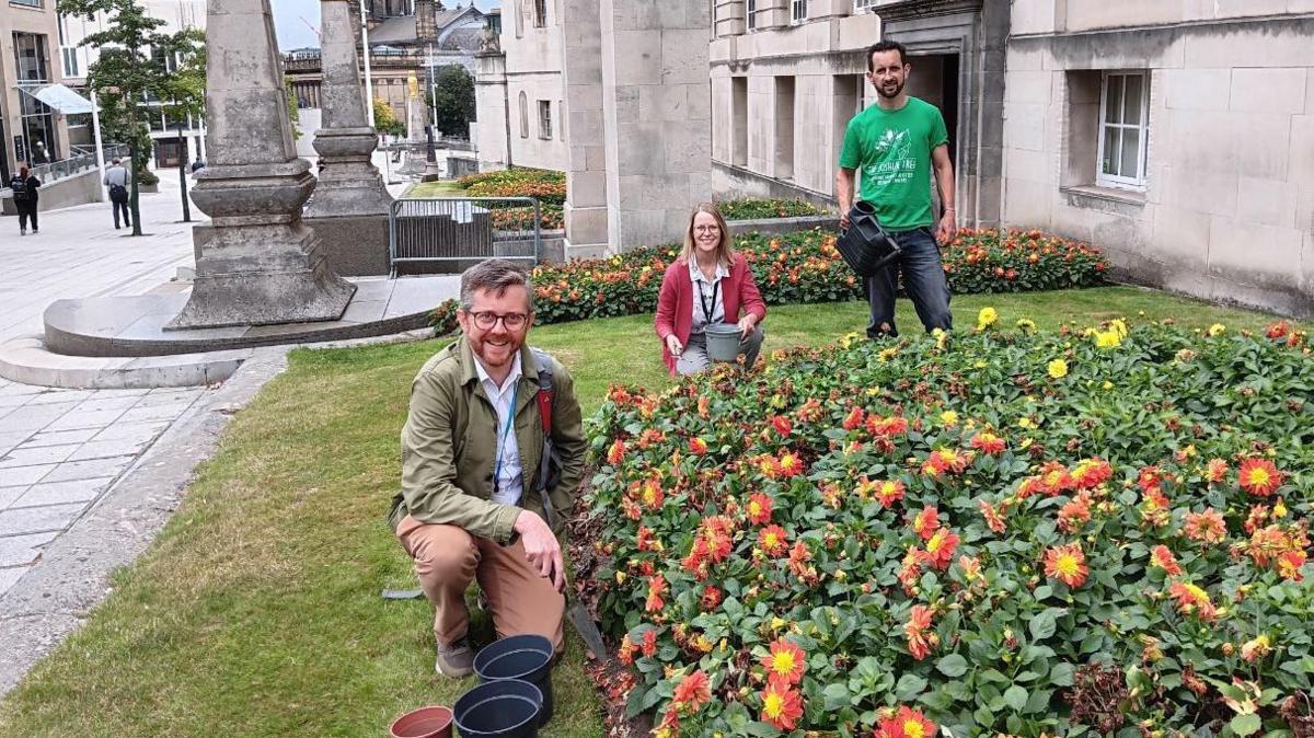 Green councillors (L to R) Tim Goodall, Penny Stables and Ed Carlisle by flower beds next to the Civic Hall 
