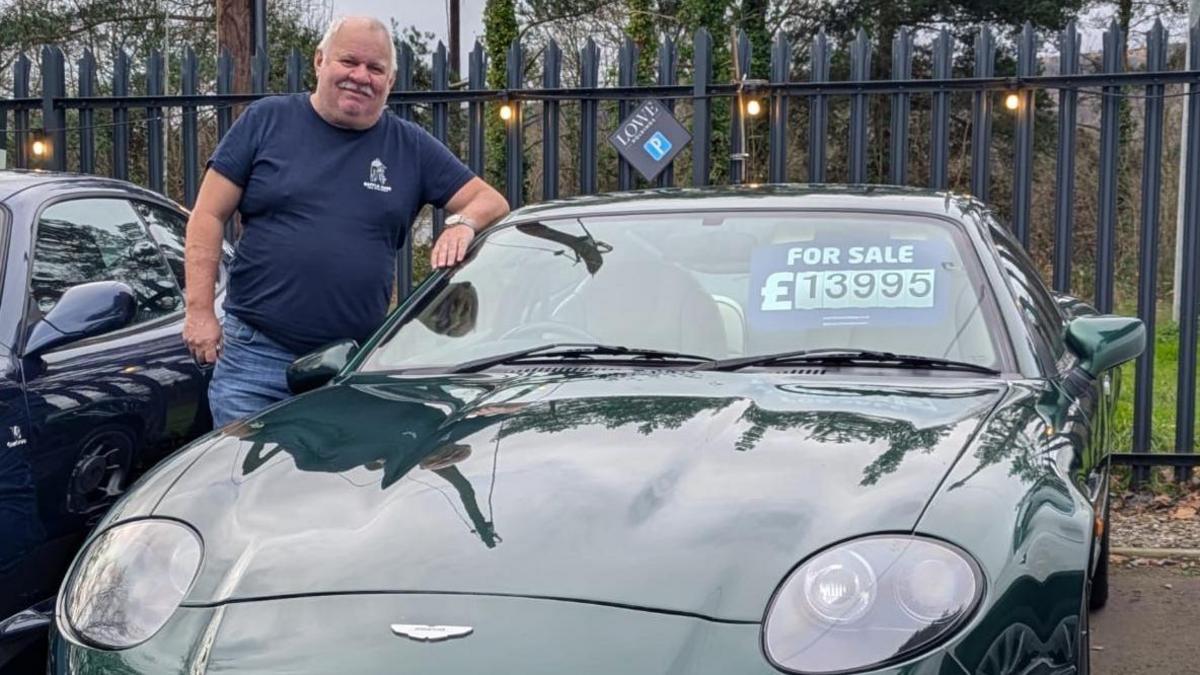 Andrew Jenkins, film producer, stands next to his green Aston Martin car