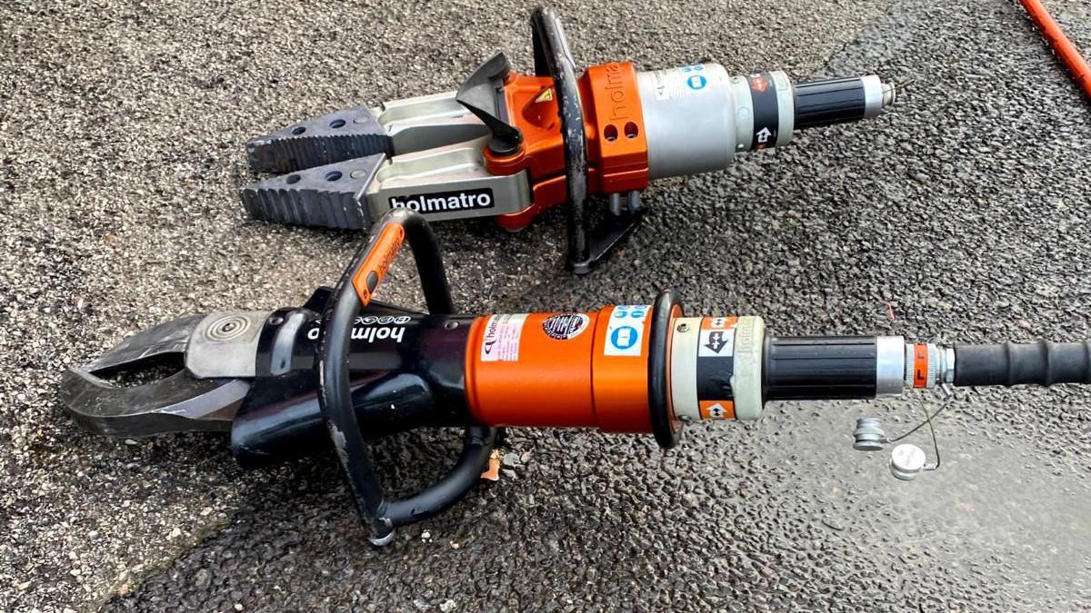 Two black and orange 'spreader' tools laid on the ground.