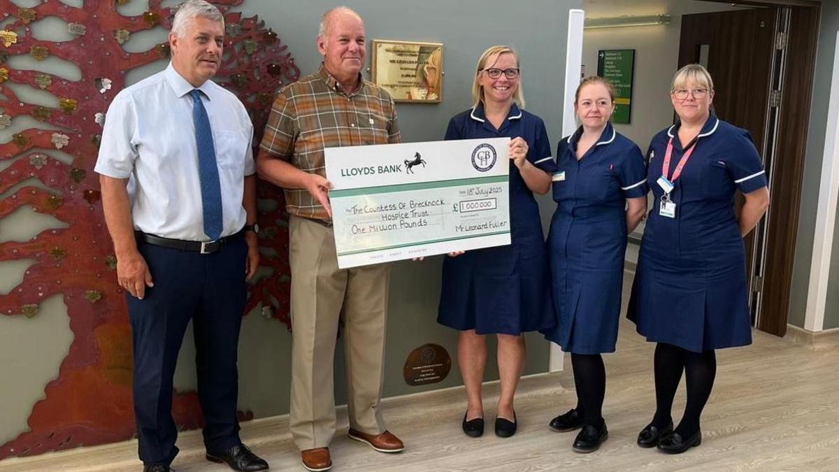James Adams alongside the hospice staff at the Countess of Brecknock Hospice - they are holding a large cheque for £1 million