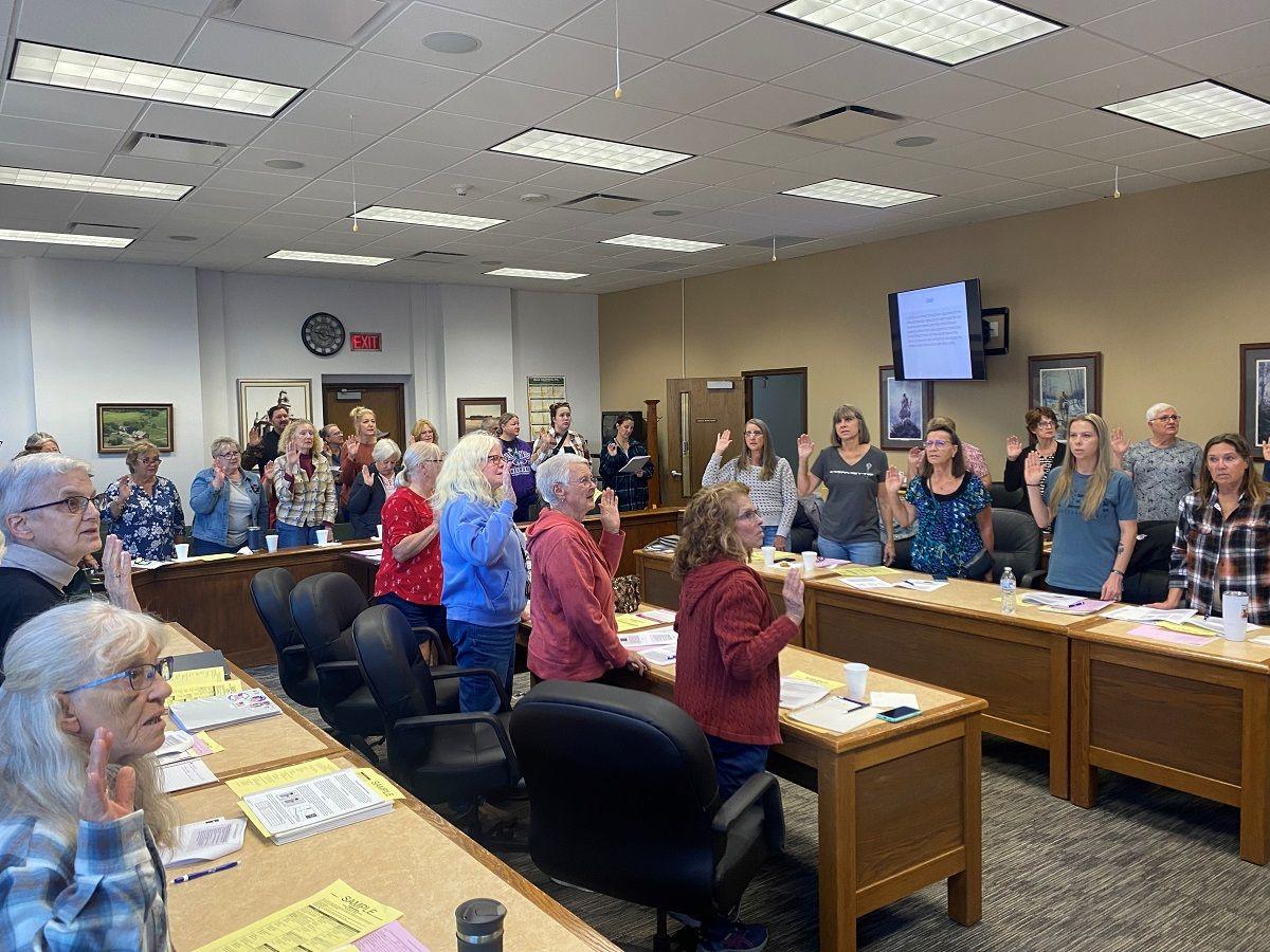 A group of mostly women, casually dressed, in a municipal office, all raising their right hands.