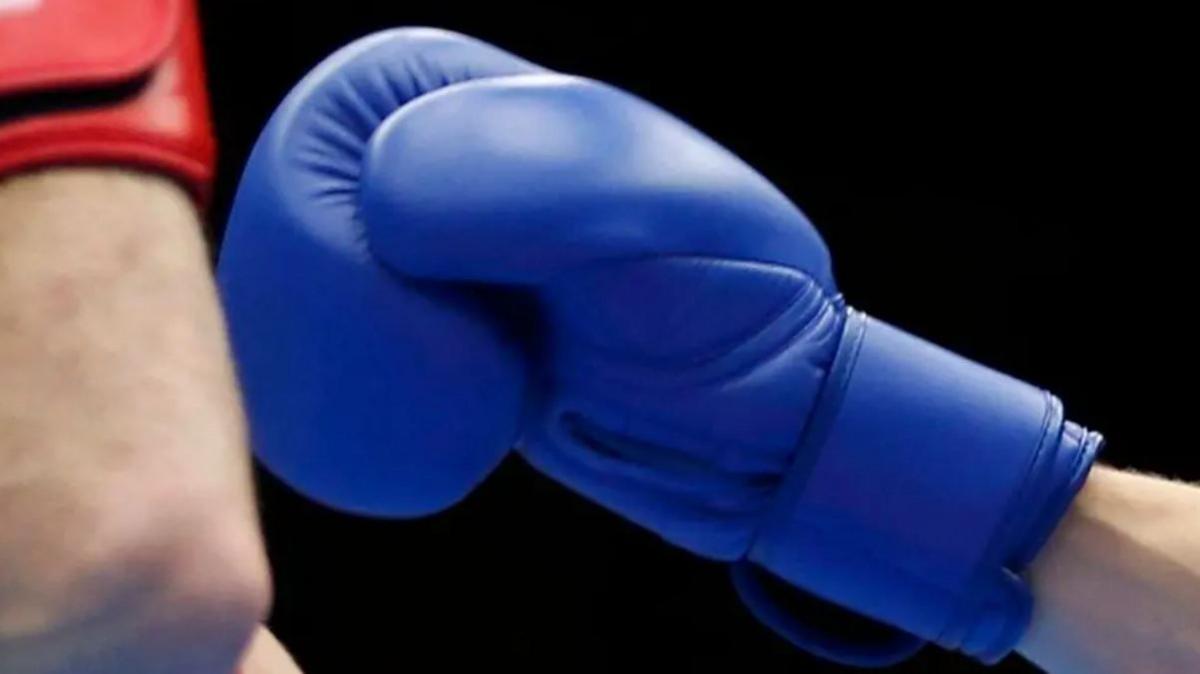 Close up of a blue boxing glove held up towards a red boxing glove in a boxing ring