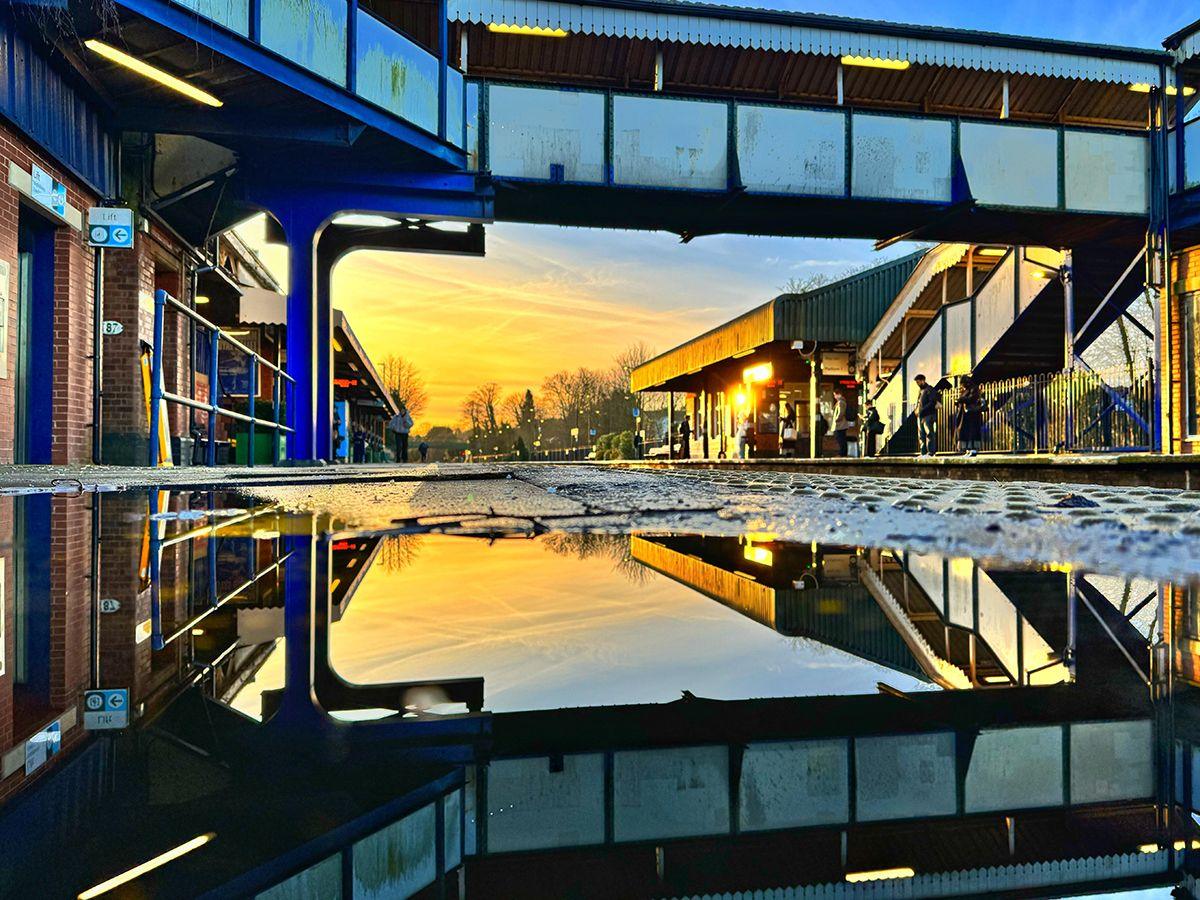 A bridge between two platforms at the station in Dorridge reflected in the surface of a pool of water