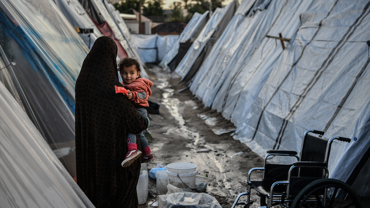 Palestinian people are seen among tents in Rafah