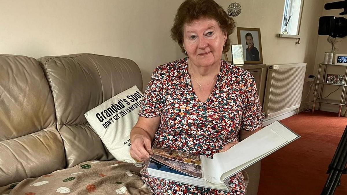 Karen Johnson sitting on a sofa with a photo album