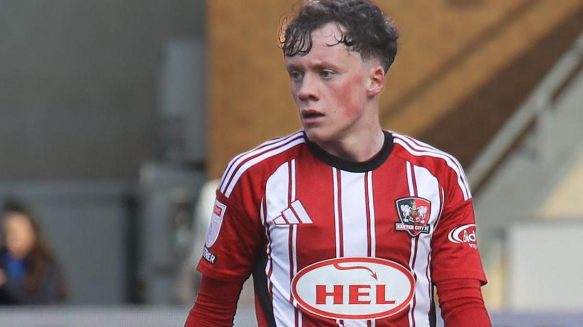 Ethan Brierley in action for Exeter City wearing their red and white striped home jersey