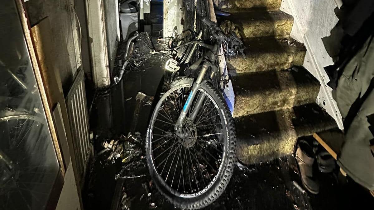 The wreckage of a house fire with a burned e-bike in the downstairs hallway.