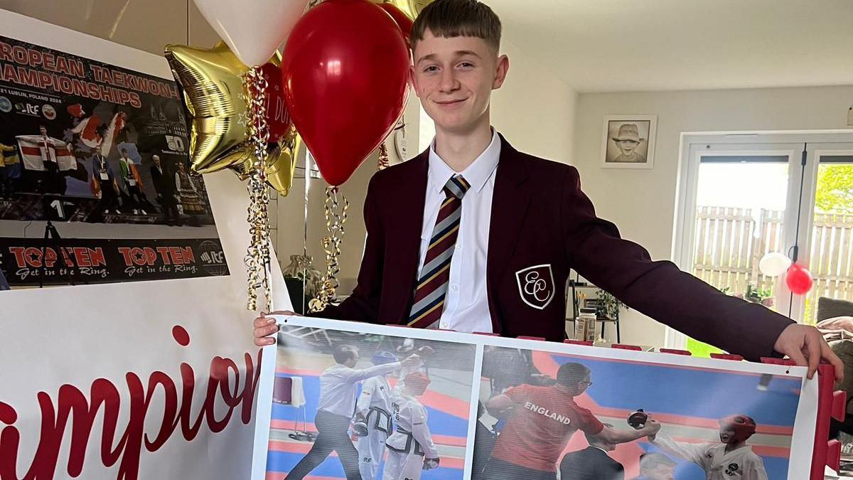 Jay Pringle standing at school with balloons behind him