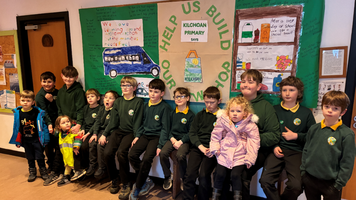 Clann-sgoile Chille Chòmhain agus postair a rinn iad air an cùlaibh a' sireadh taice don iomairt bùth ùr a thogail 