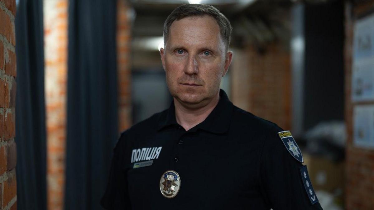 Police Colonel Serhii Bolvinov stands in uniform staring into the cameraman