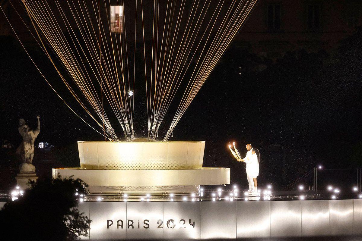 The torchbearers Marie-Jose Perec and Teddy Riner (R) walk to light up the Paris 2024 Hot-air Balloon Olympic Cauldron during the Opening Ceremony of the Paris 2024 Olympic Games