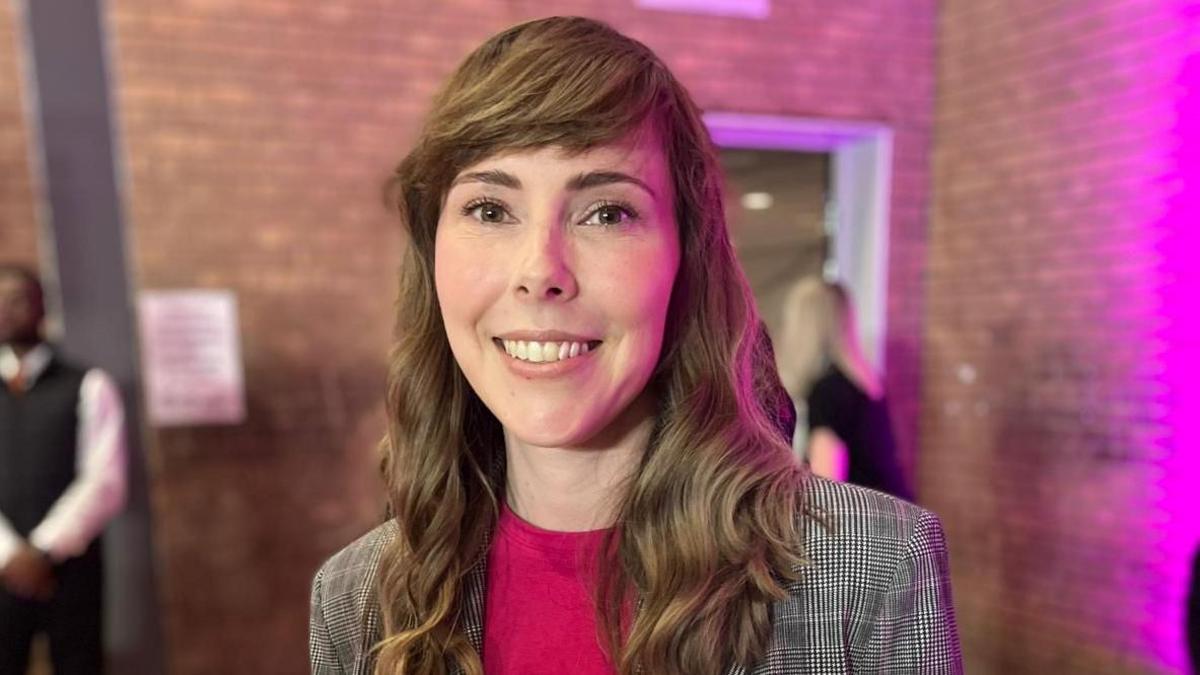 A woman with long brown hair smiles at the camera