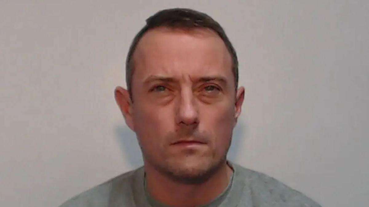 Police custody image of Jamie Cassidy with brown hair wearing a grey t-shirt.
