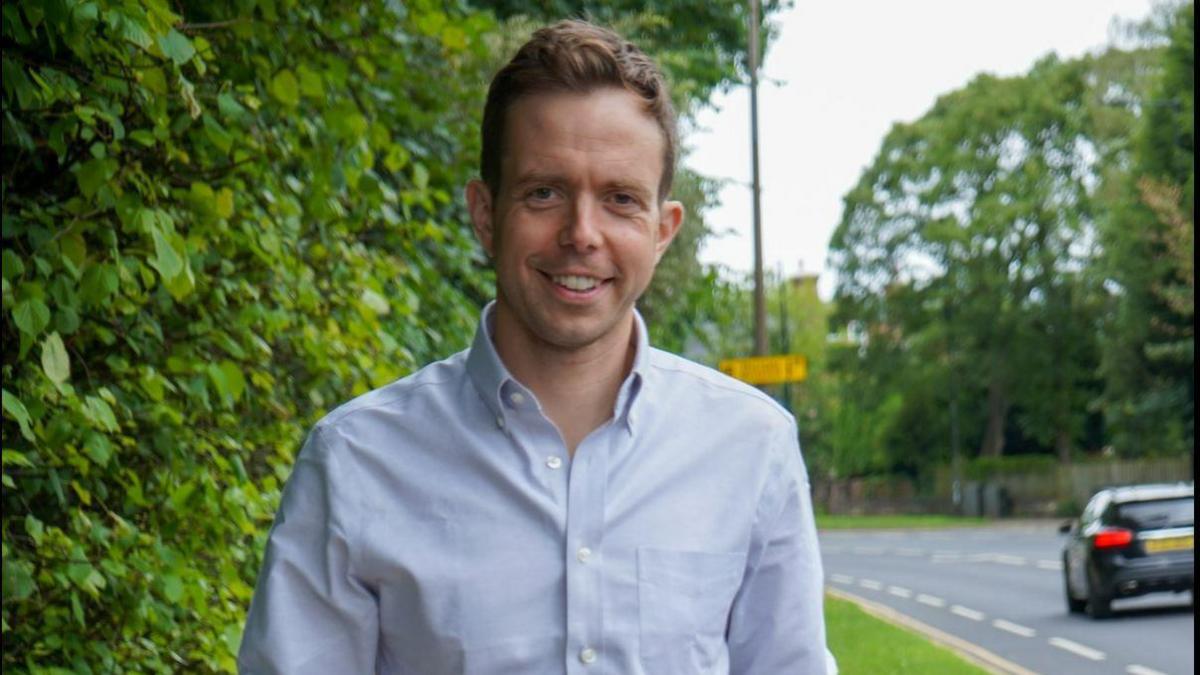 Rother Valley MP Jake Richards, wearing a blue shirt, stands by a roadside