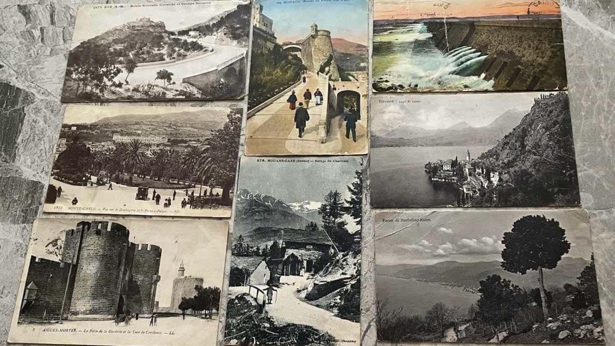 A picture of all eight postcards laid out on a worktop, they show black and white images of places around the world and two in colour