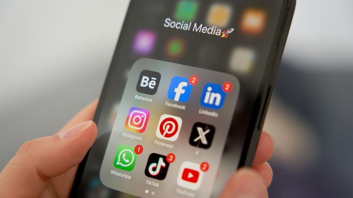 A black phone with social media apps in a group on the screen.