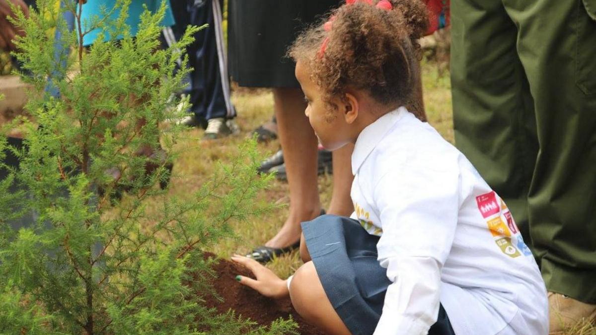 An archive picture of a young Ellyanne Wanjiku Chlystun planting a tree.