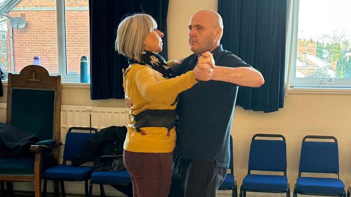 Amanda Parker and Lee Roberts in the starting position where they face each other. Mr Roberts' left hand holds Ms Parkers' right hand, and his right hand rests on her left shoulder. Ms Parker's left hand rests on Mr Roberts' shoulder.