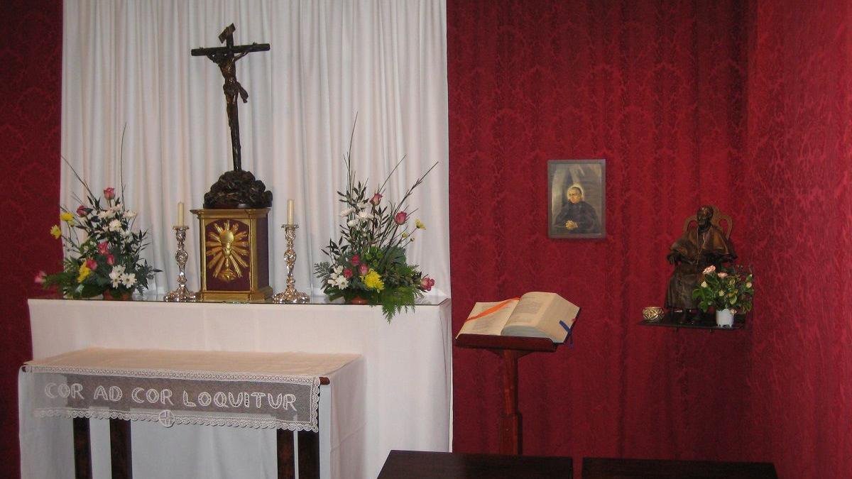A small chapel with red and white cloth walls, floral arrangements and a cross depicting Jesus's crucifixion.