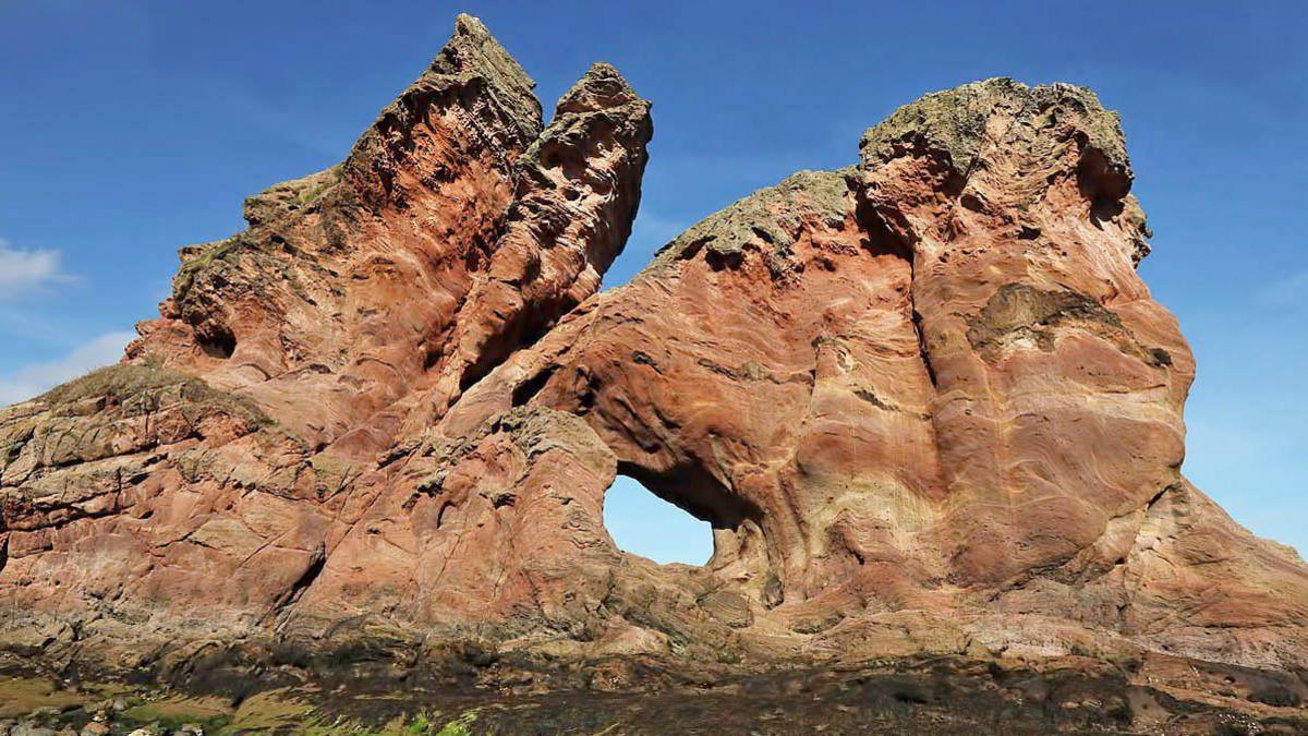 A striking rock formation jutting up into a blue sky in the Borders