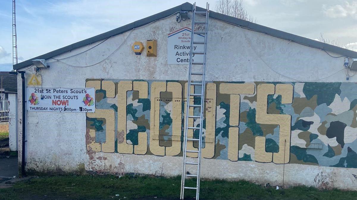 The Whitley Bay scout hut, a one-storey building with a ladder up to the roof and the word Scouts in large letters on the side. 