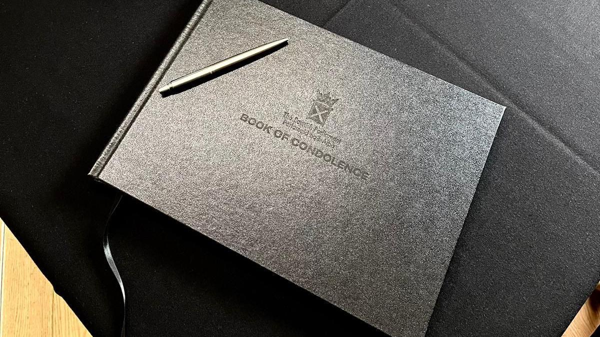 A black book of condolence sits on a black table.