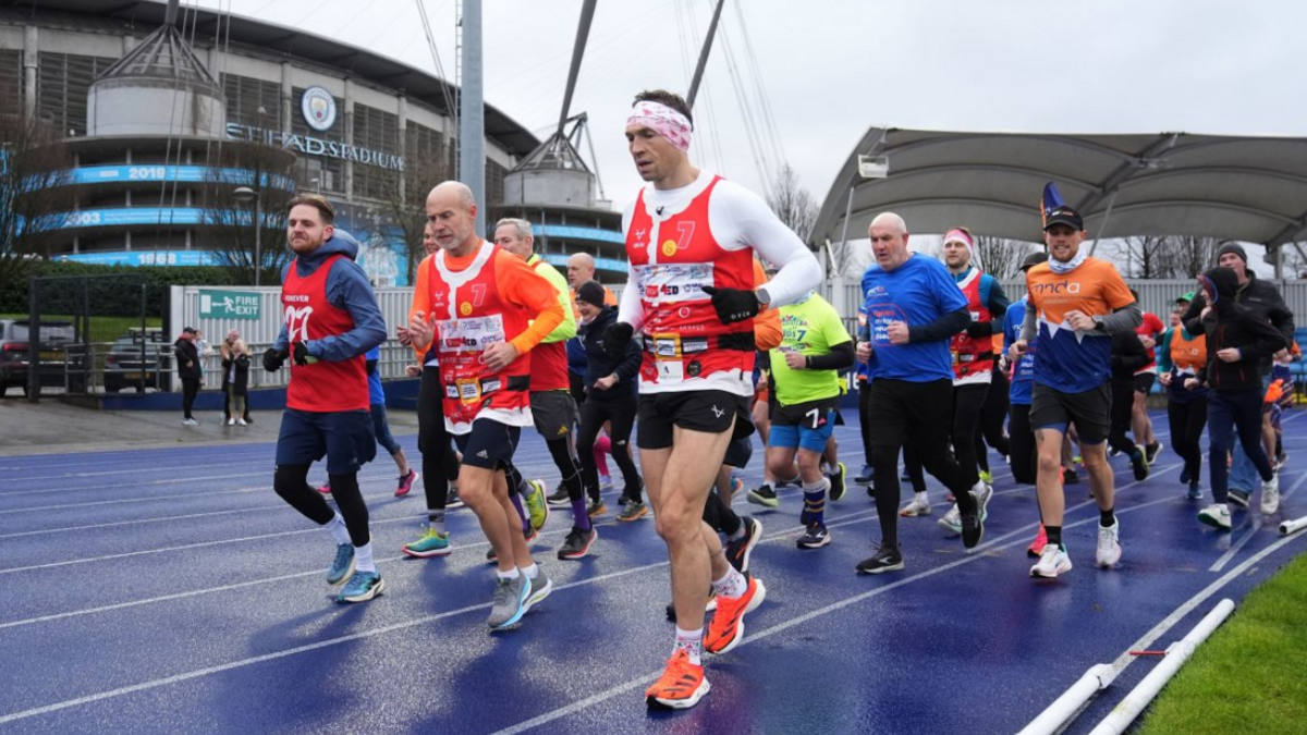 Sinfield with his head down running past Manchester City's stadium with supporters