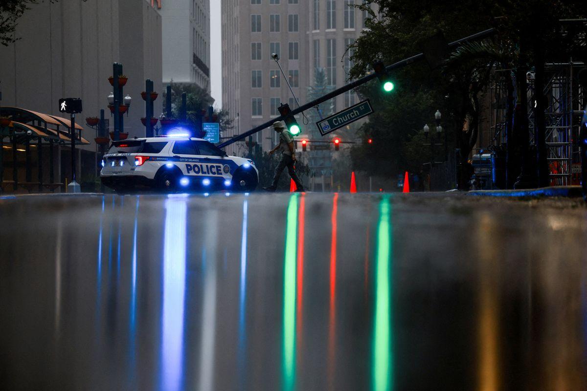 A view shows light falling over a wet street with a fallen traffic light near a police car in the background in Orlando, Florida, U.S., October 10, 2024