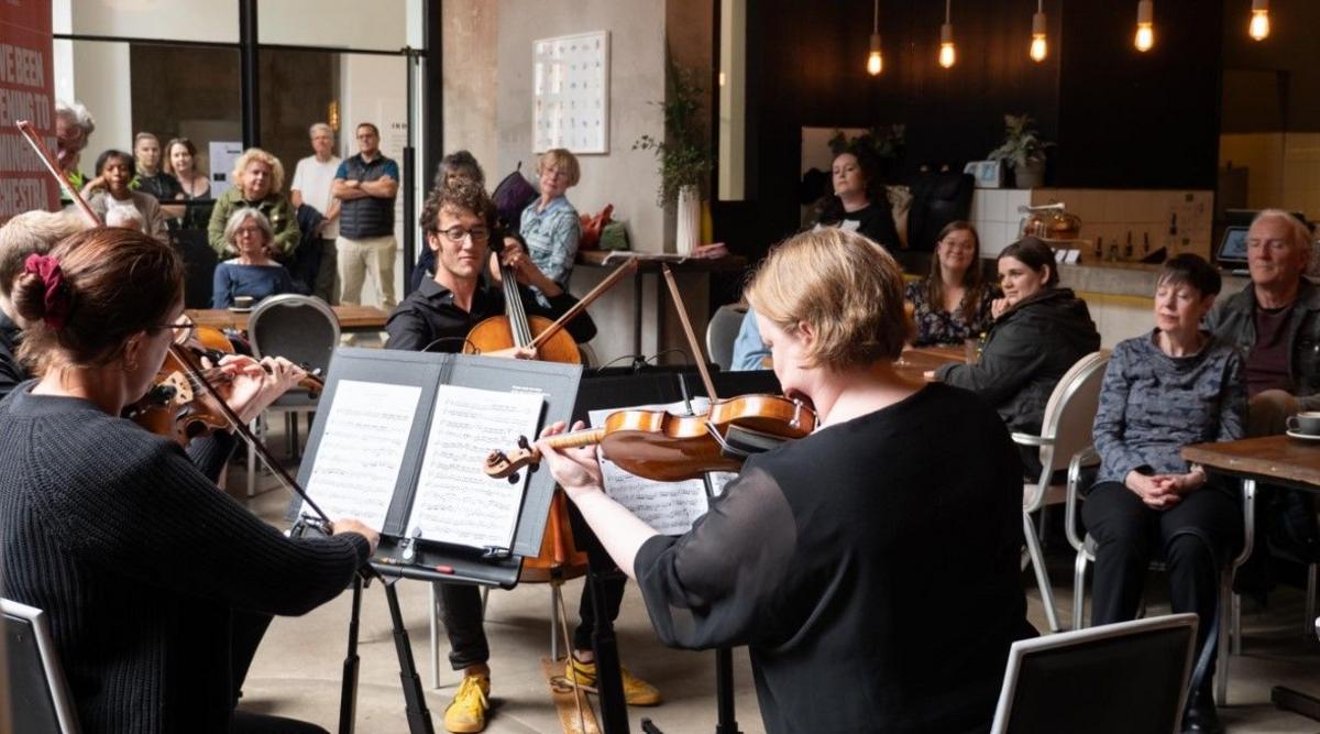 A string quartet performs in a cafe while customers watch