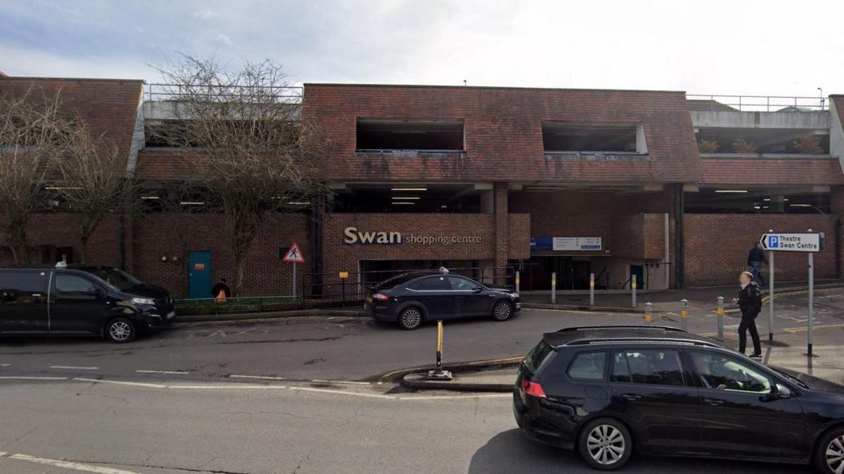 The carpark of a red brick shopping centre. 