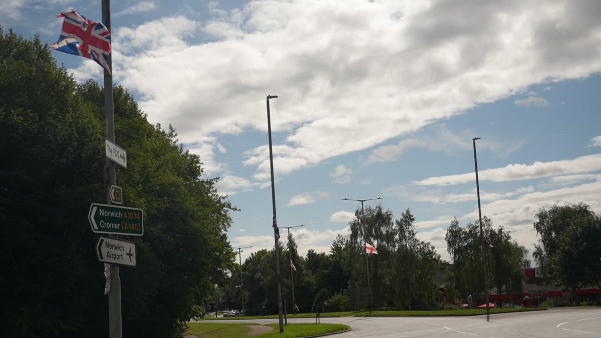 A road junction with several lamposts, some of which have the Union flag or St George's cross flag attached to them