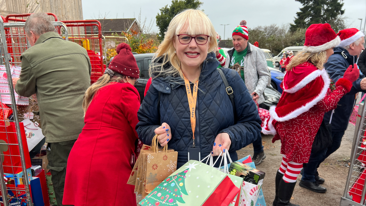 Sally Hillyear who is the Director of Fundraising at Southampton Hospitals Charity is standing in the hospital car park surround with bags of Christmas presents.