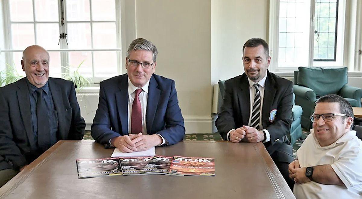 John Morris (left) and Keir Starmer (second from left) sit at a table with two other men, including Labrats campaigner Alan Owen (right) Steve Purse, (far right). Displayed on the table are copies of a magazine called Atom.