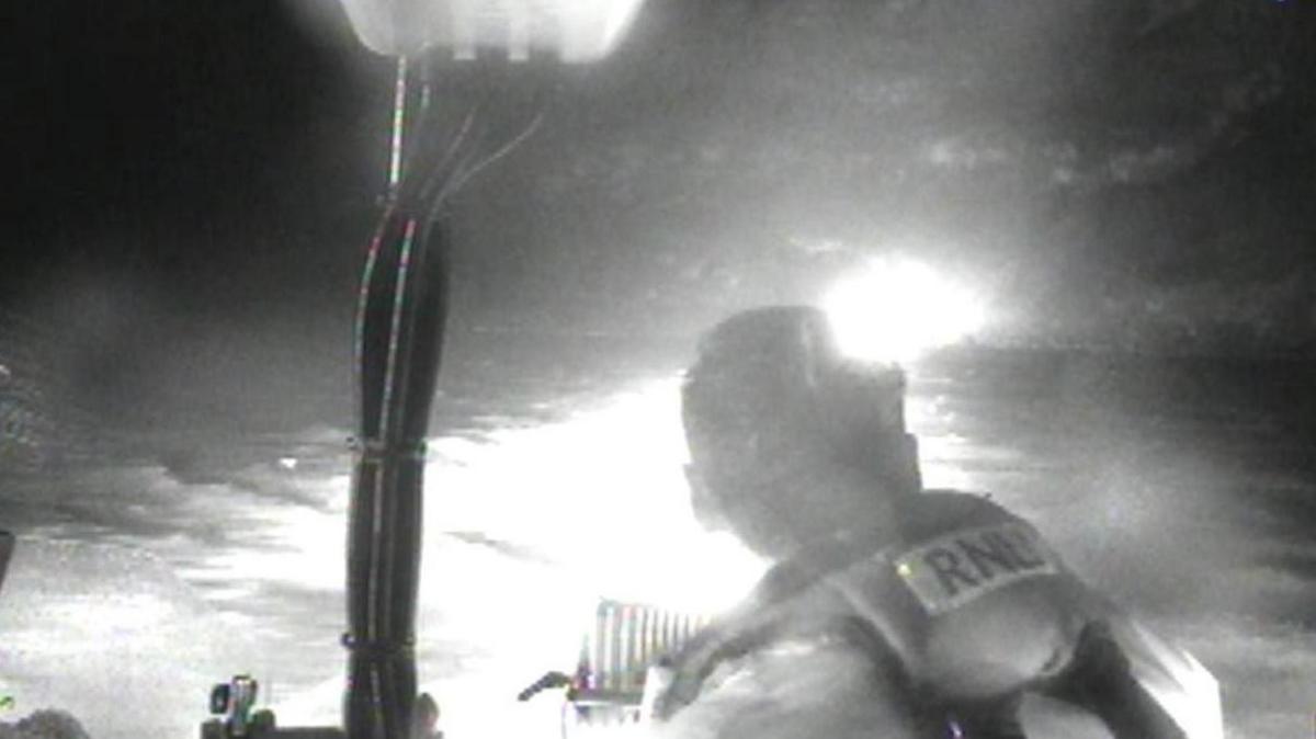 A blurry black and white photo showing an RNLI crew member and bright lights.