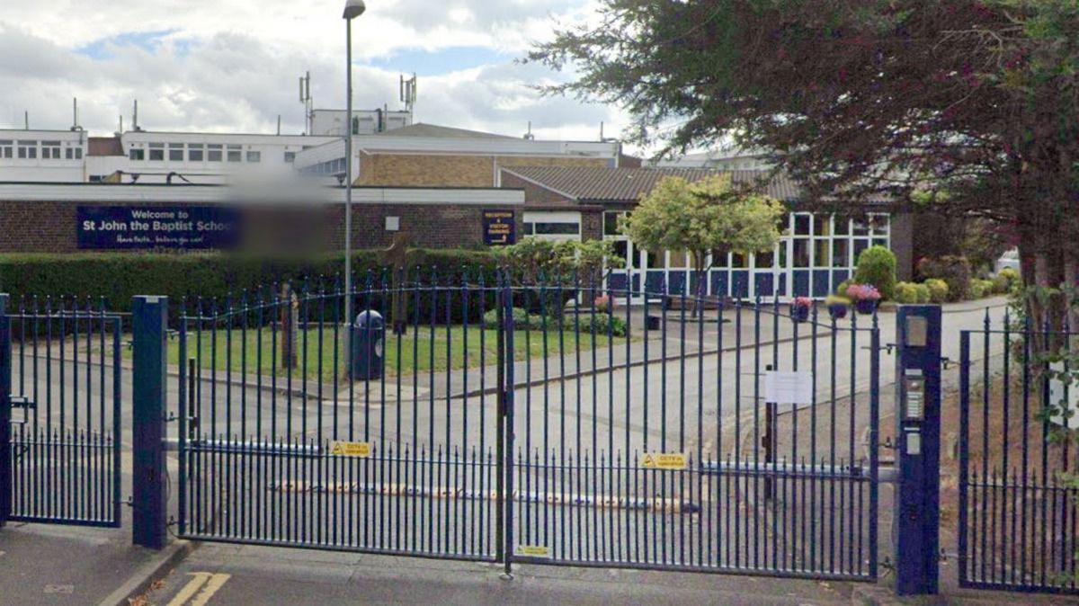 A google street view of St John the Baptist School behind a blue fence