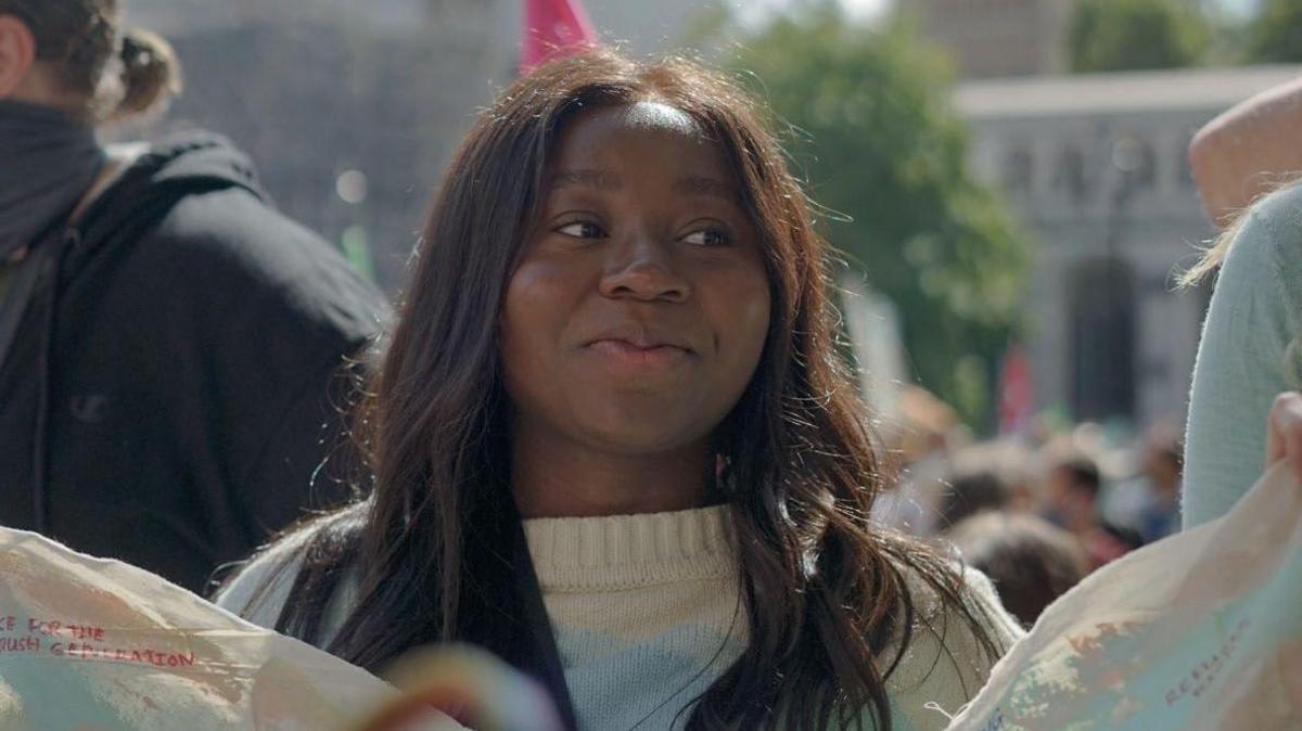 Daze Aghaji, a young woman in a white jumper, with long hair, smiling at a demonstration