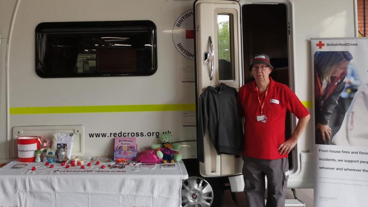 Steve Bradley, wearing a British Red Cross polo shirt, stands in front of an ambulance at a charity event