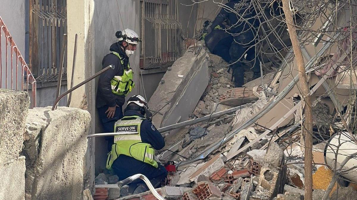 Volunteers in uniform and helmets searching in rubble