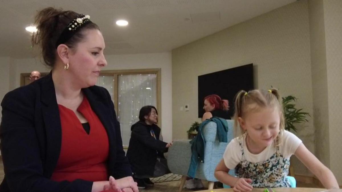 Sarah Kilcoyne sitting next to seven-year-old Mia at a table where they are playing games