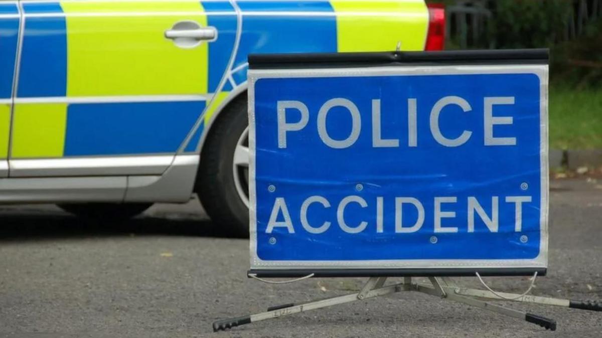 A blue police accident sign propped up on the road in front of a parked police car