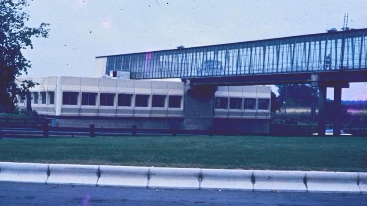 A slightly grainy picture of a service station with a footbridge over the motorway.