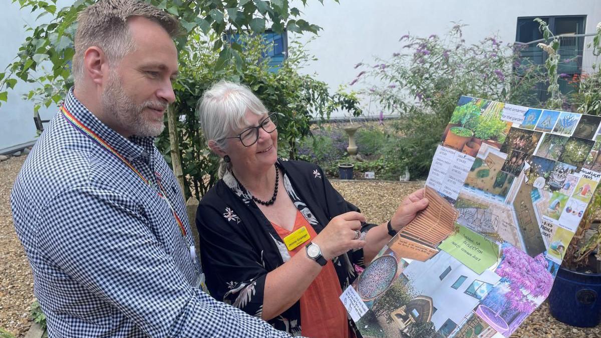 Jennie Grainger and Philip Fearn, who are both involved in the project, holding the design posters