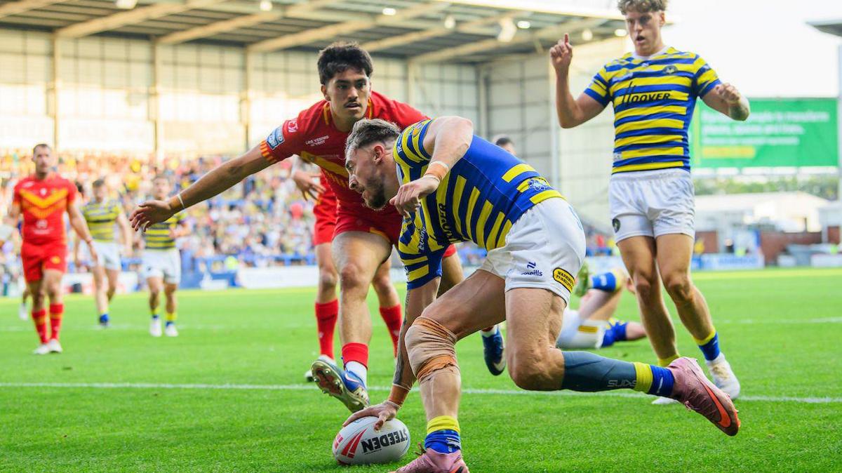 Matty Ashton touches the ball down for a try for Warrington as the Catalans defence arrives too late.