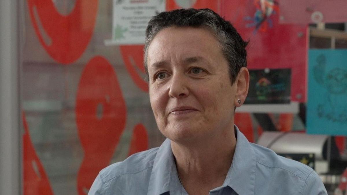 Dr Sara Hanna in a blue shirt sat next to a toy on a table. 
