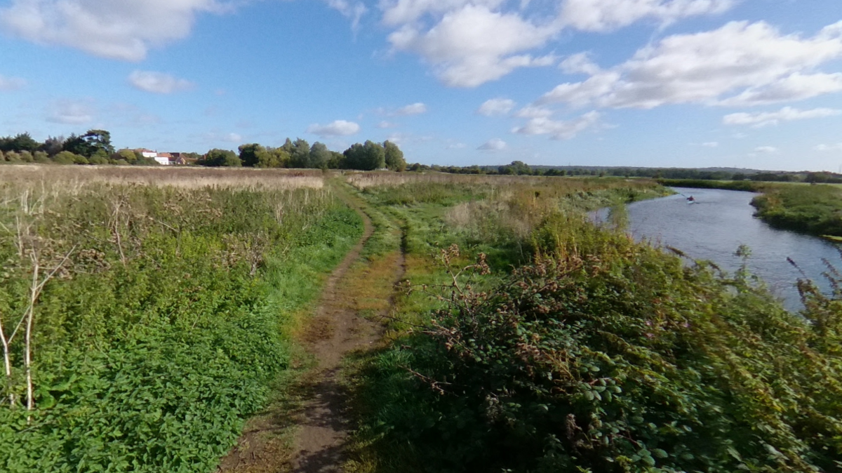 landscape with natural path and wild scrub with a river snaking around the right hand side