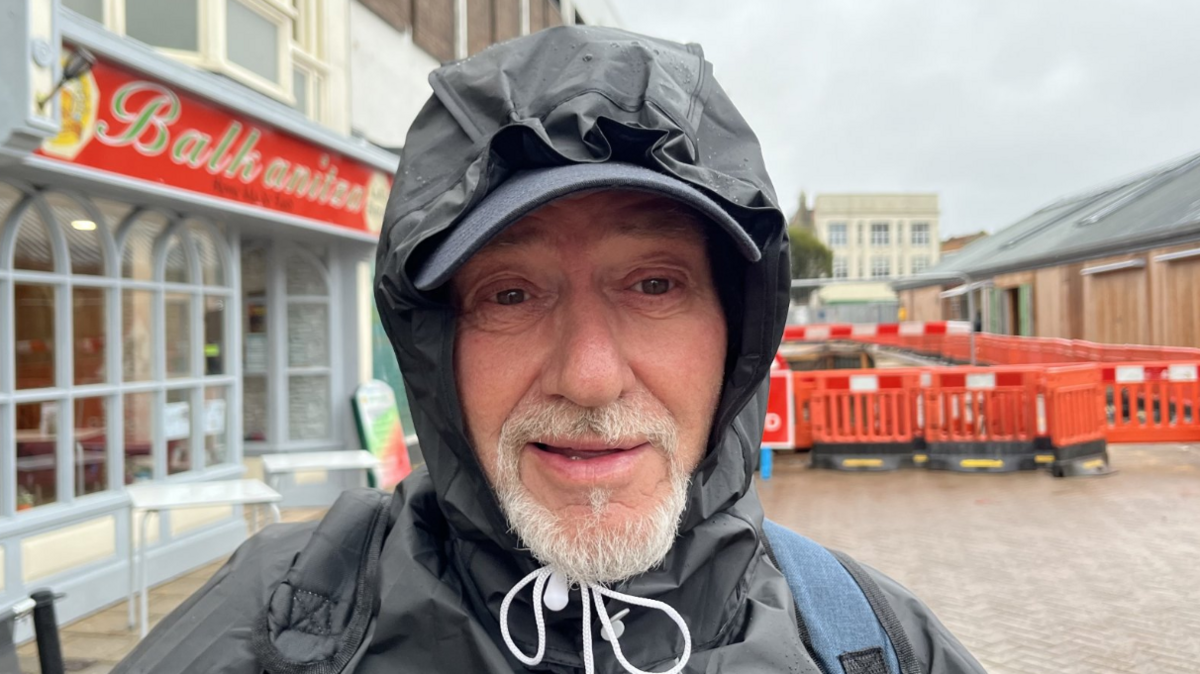 Lee Ray with a grey beard and a black hood over his head and tied under chin with white cord