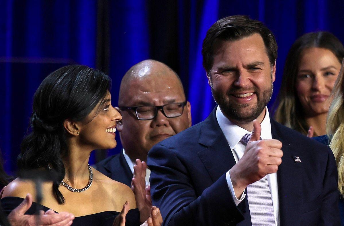 Usha Vance in a sleeveless dress looking at JD Vance who is giving a thumbs-up sign